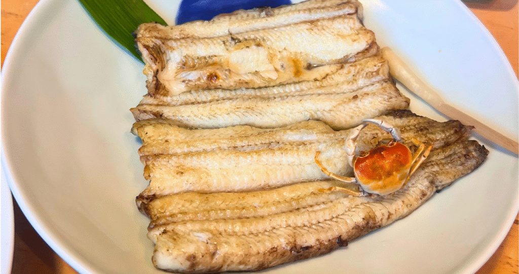 友栄の白焼き。香ばしく焼き上げたうなぎに小さなカニが添えられている。
