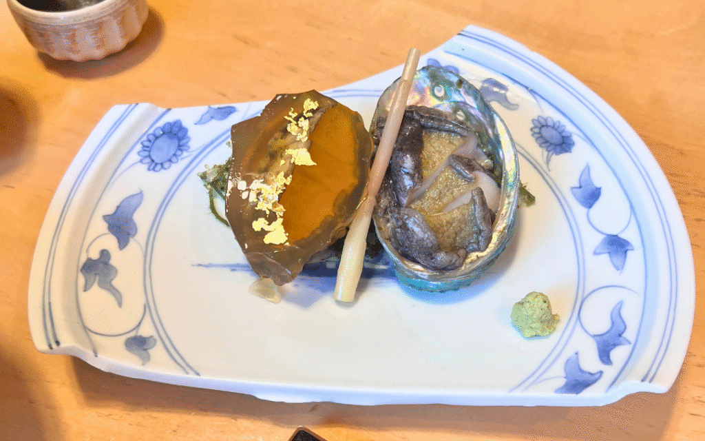 友栄のあわび刺身と金箔をあしらった煮こごり。上品で風味豊かな前菜。
