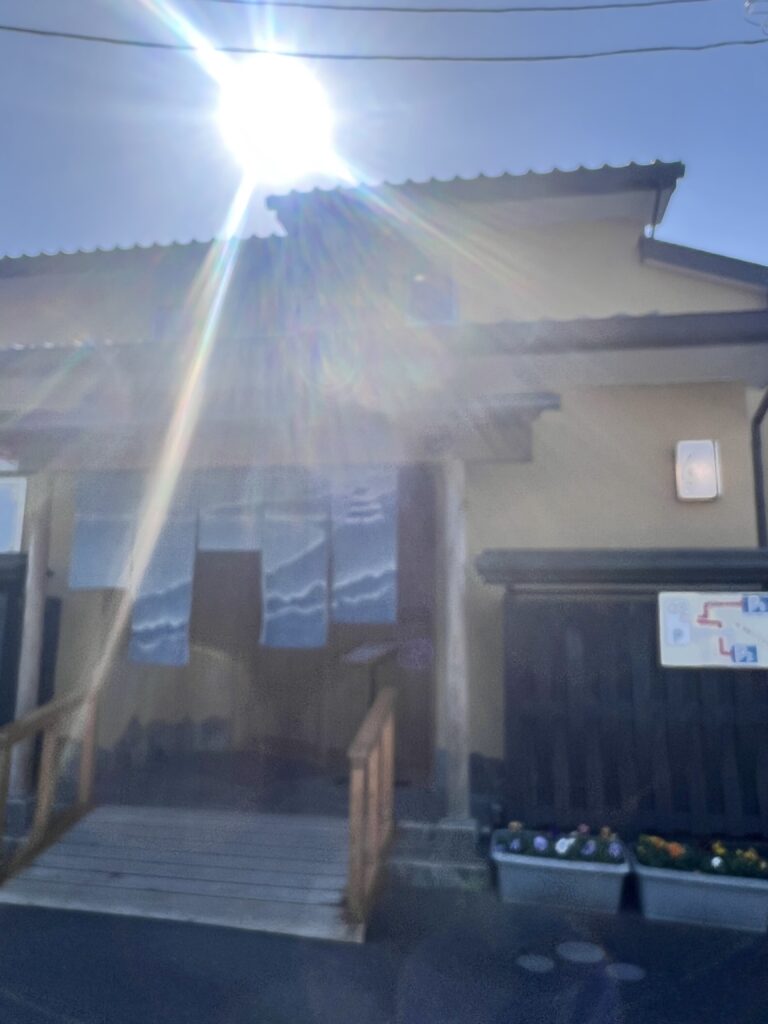 箱根・友栄の外観。秋の強い日差しと暖簾が揺れる落ち着いた和の店構え。
